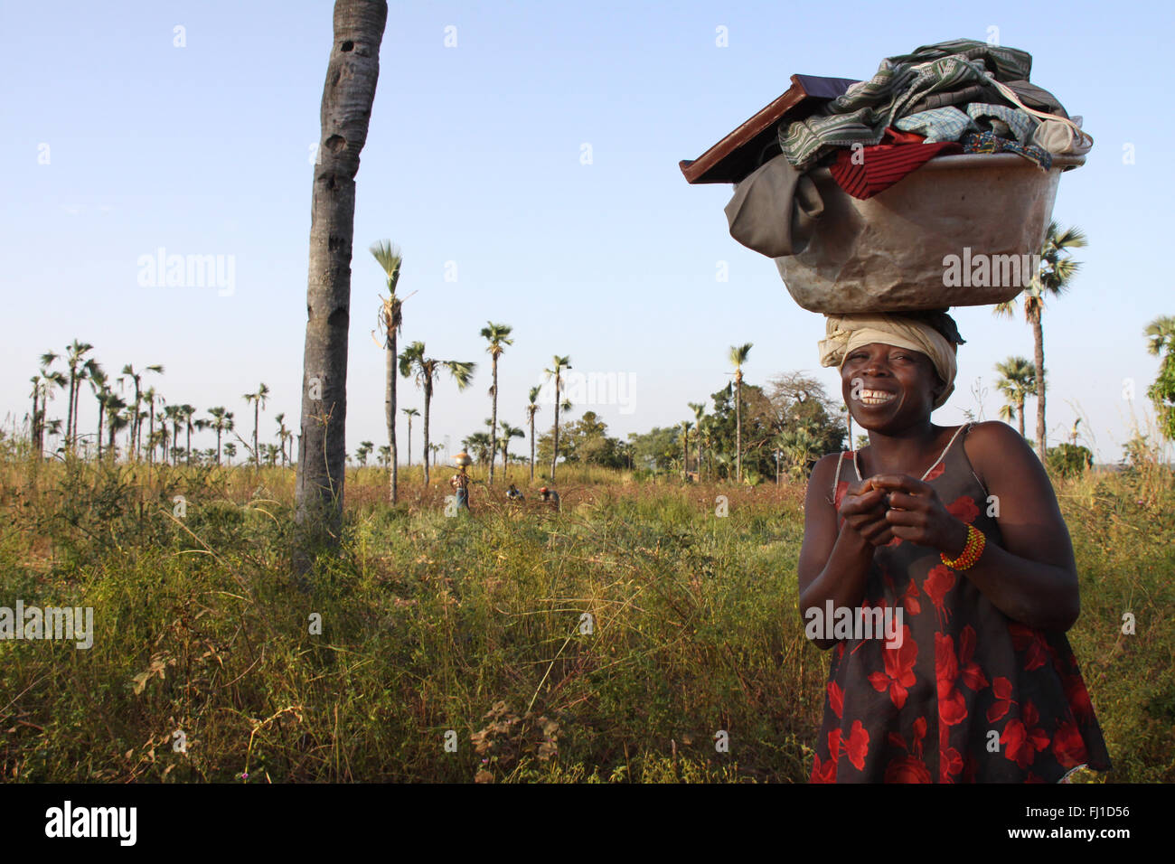 Frau mit Korb auf dem Kopf und gehen in den Wald und Felder in den frühen Morgenstunden in der Nähe von Banfora in Burkina Faso zu arbeiten Stockfoto
