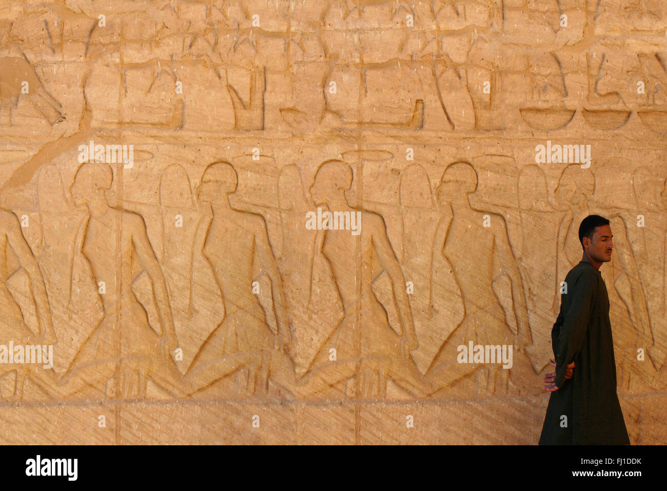 Ein Mann Spaziergänge entlang der Wand schnitzereien vor Abu Simbel Tempel, Ägypten Stockfoto