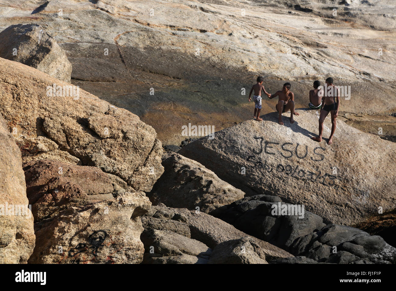 Brasilianischen Jungs in der Nähe von Ipenama Strand mit "Jesus" schreiben auf einem Felsen, Rio de Janeiro Stockfoto