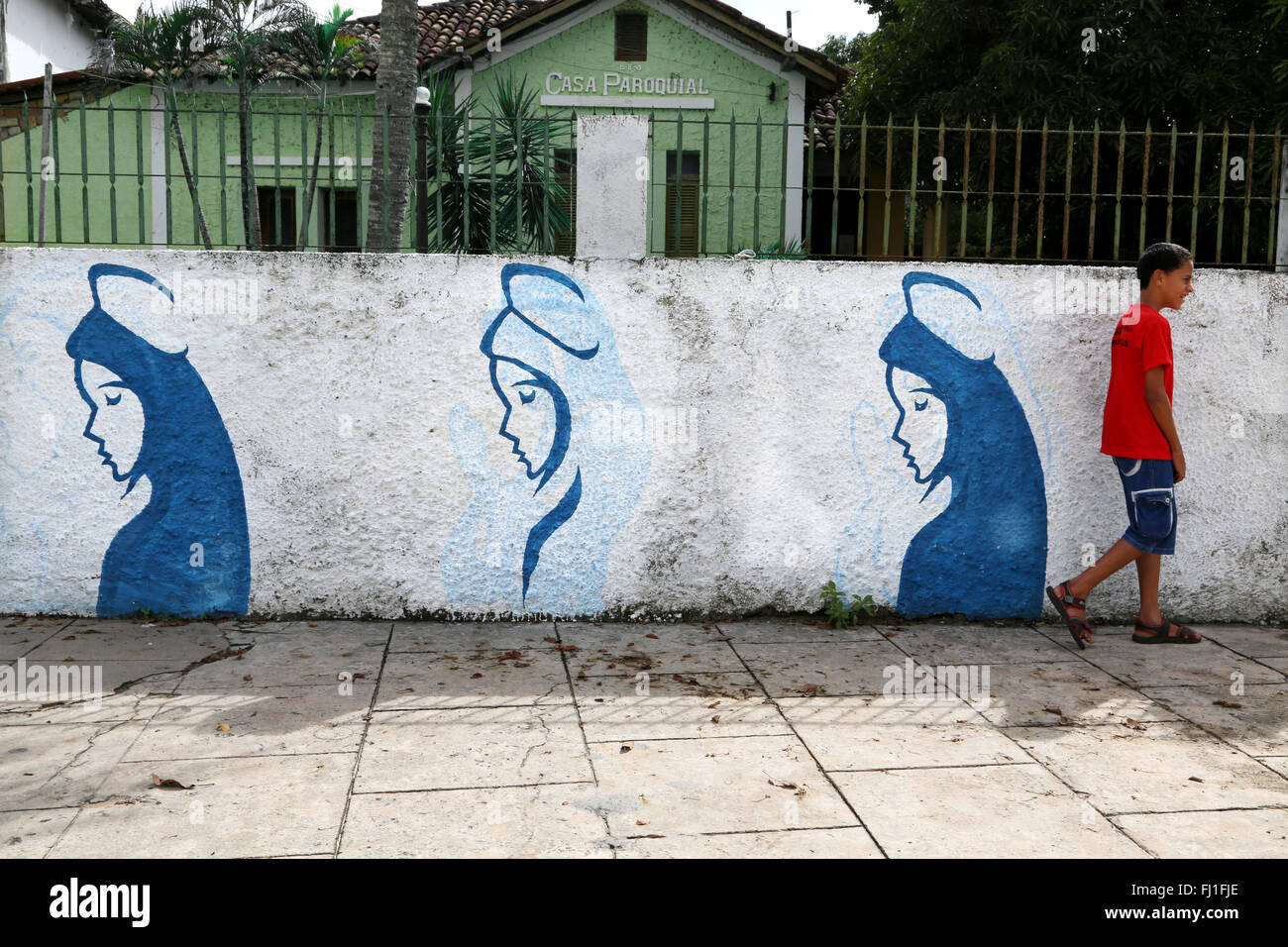 Man Walking entlang einer Wand mit Jungfrau Maria Gemälde in Barreirinhas, Maranhao, Brasilien Stockfoto