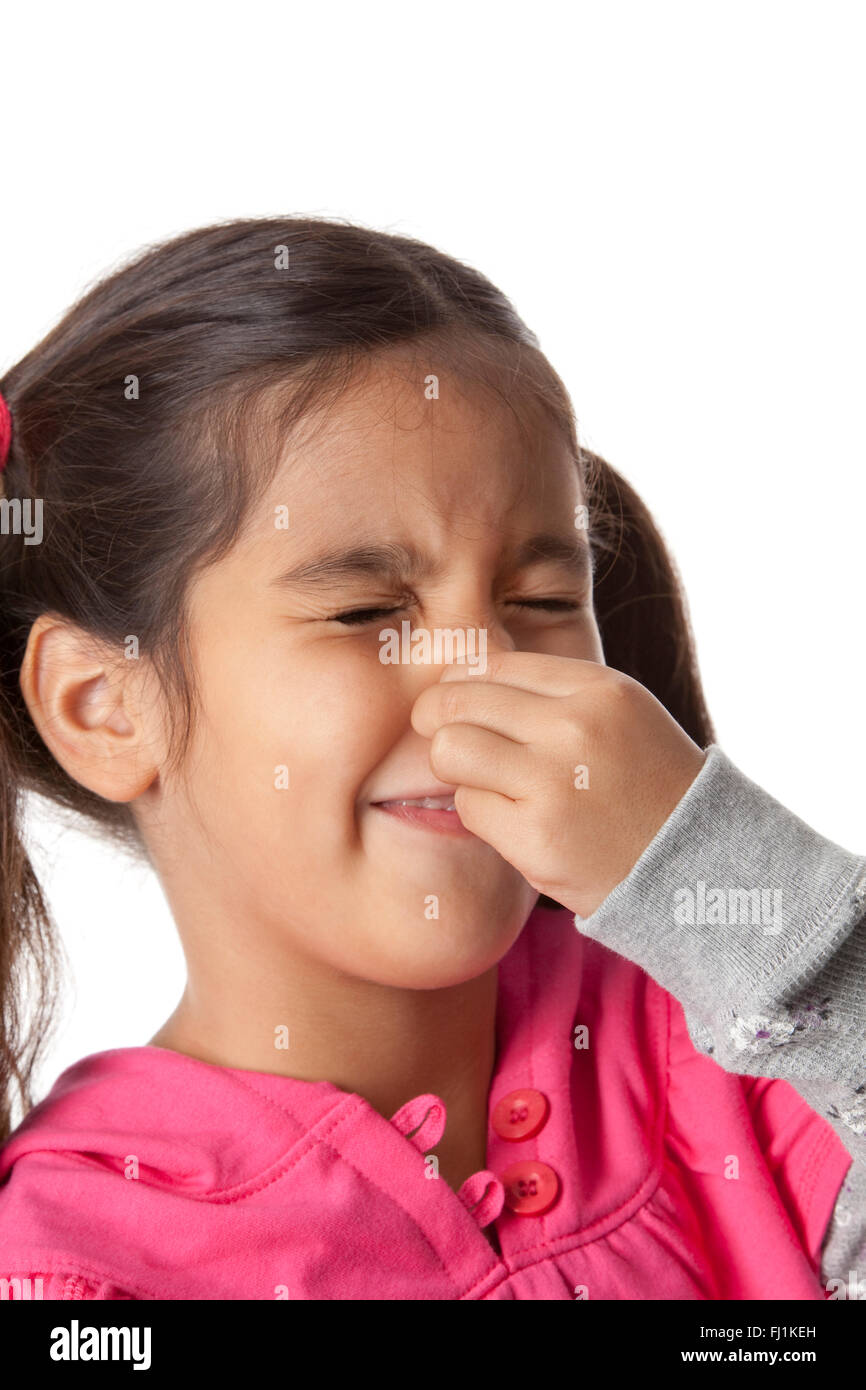Kleines Mädchen schließt ihre Nase mit den Fingern auf weißem Hintergrund Stockfoto