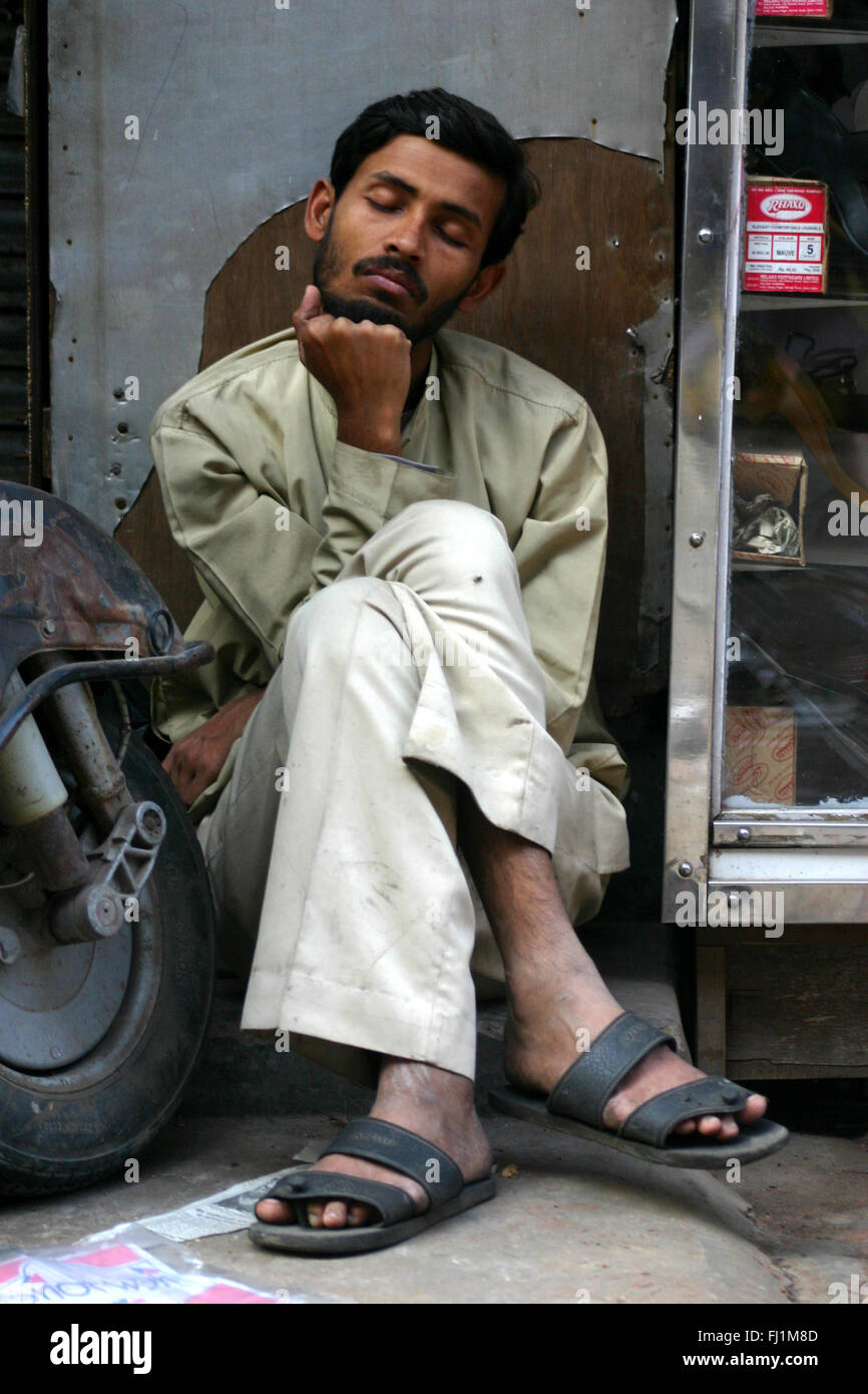 Mann sitzen und schlafen in einer Straße von Delhi, Indien Stockfoto