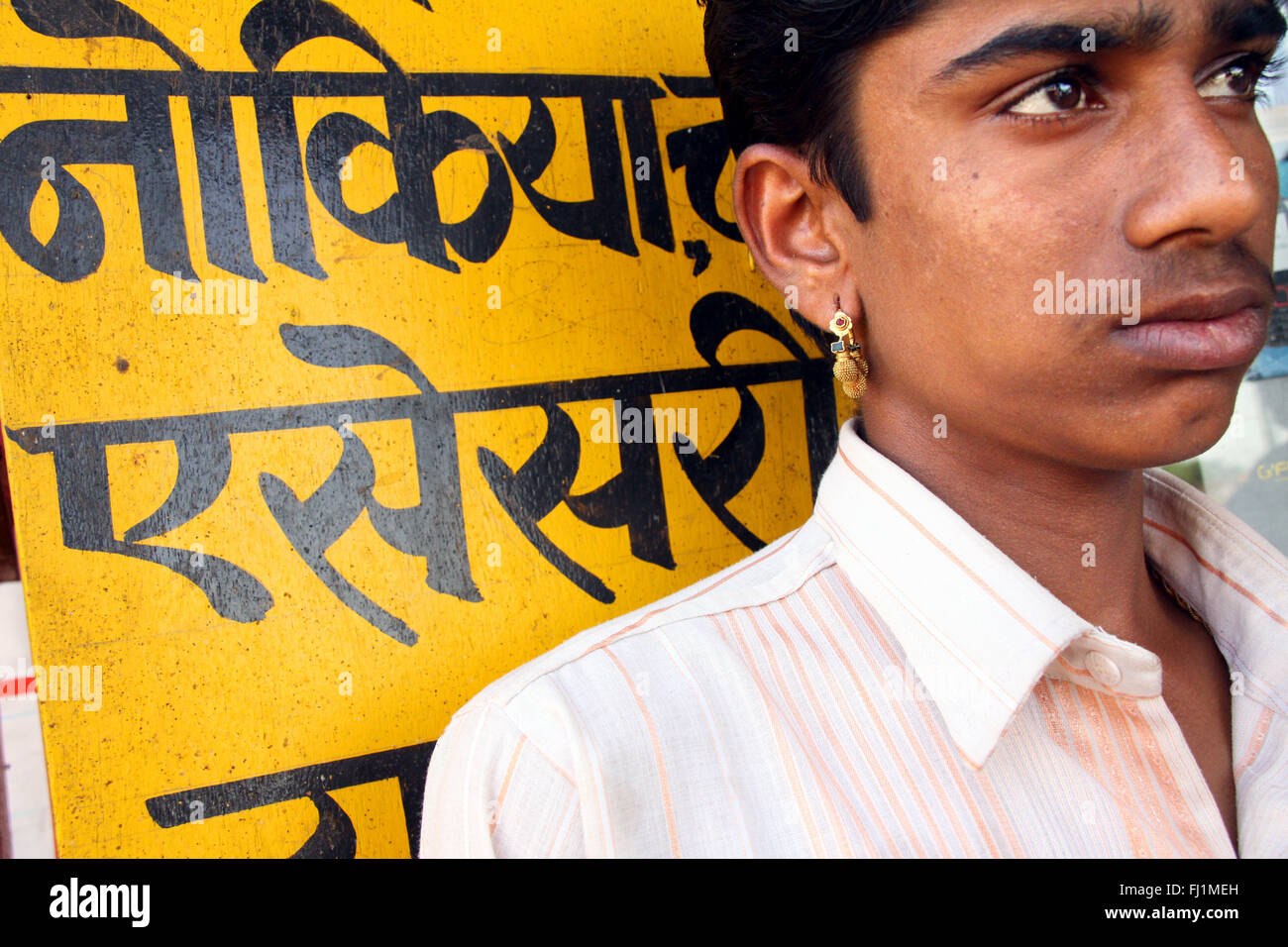 Indische Rajasthani Mann in Bikaner mit Ohrring und Hindi Schriften in Bikaner, Indien Stockfoto