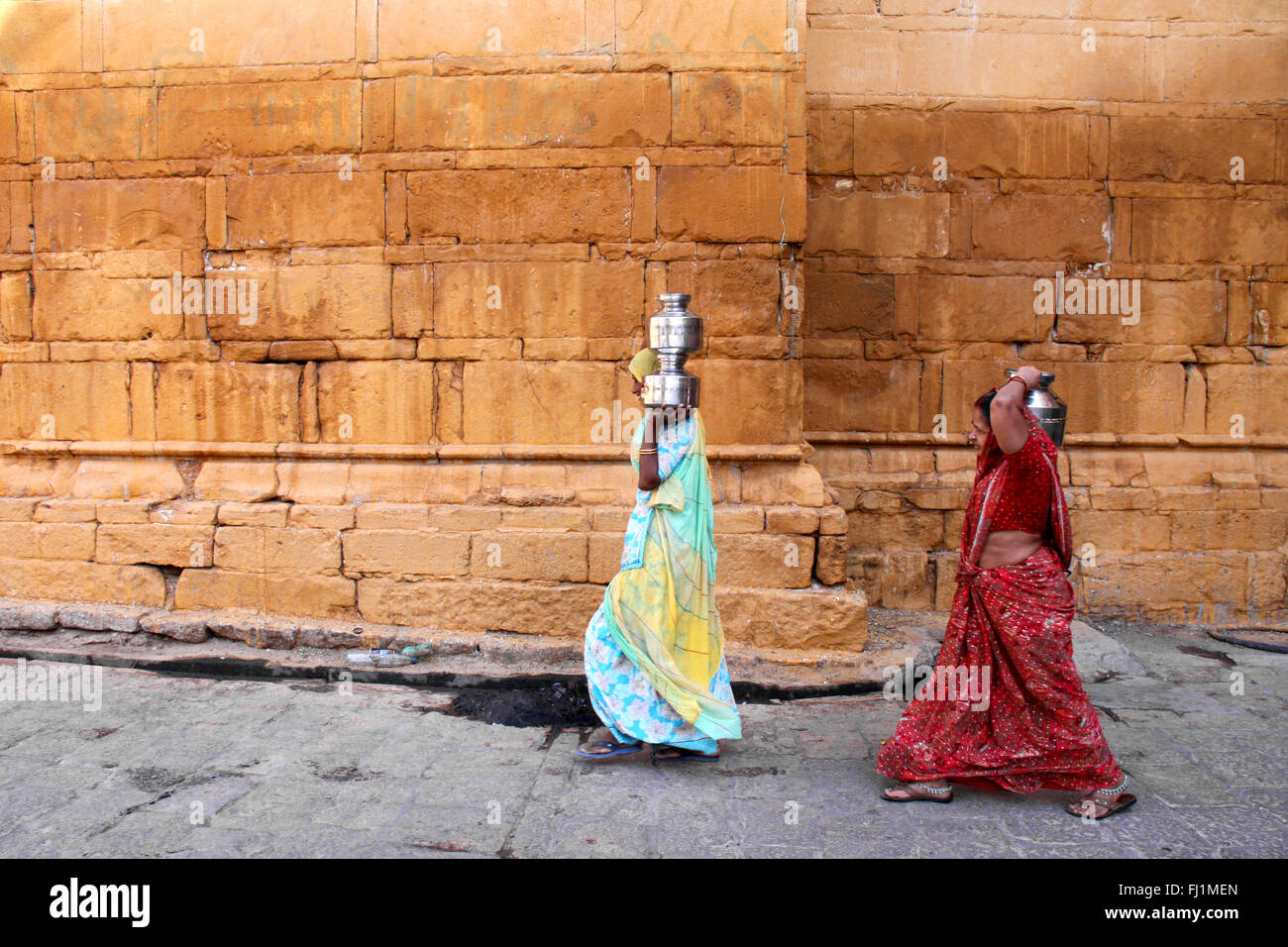 Zwei Frauen sind, die Wasser in Metall Krüge in der Straße von Jaisalmer, Indien Stockfoto