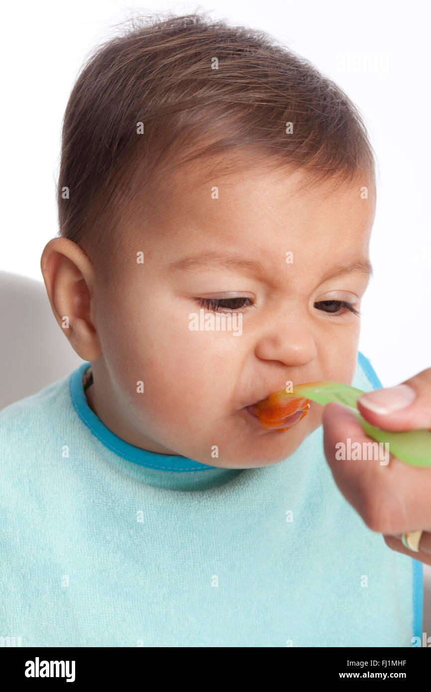 Babymädchen ist Abneigungen essen Karotten auf weißem Hintergrund Stockfoto