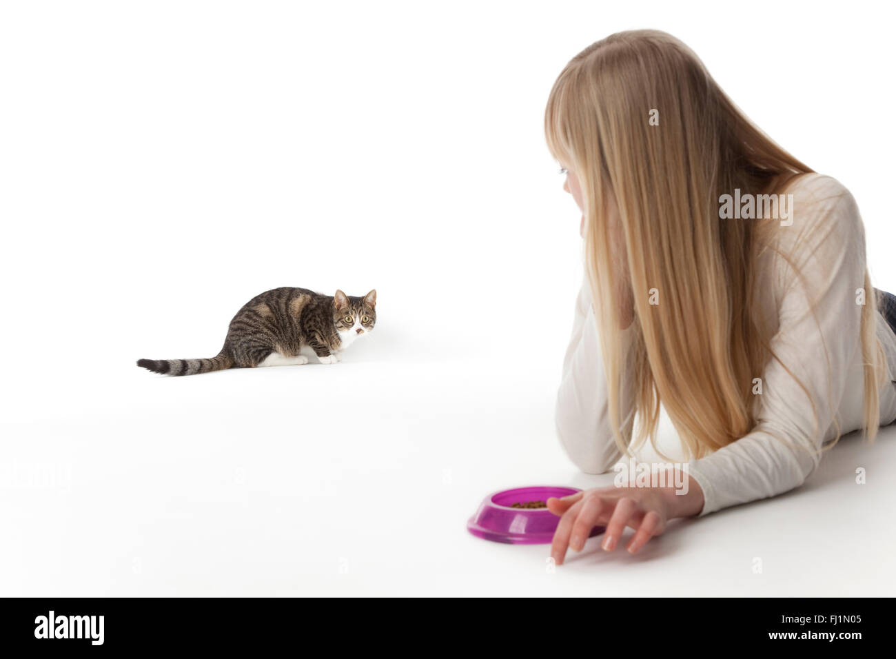Teenager-Mädchen ruft ihre Katze auf weißem Hintergrund zu essen Stockfoto