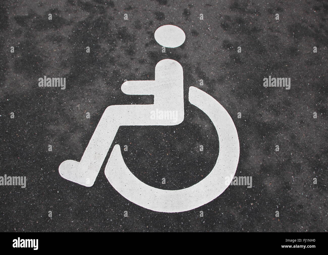 Isolierte weiße Handicap Behinderte Zeichen auf schwarzem Asphalt Stockfoto