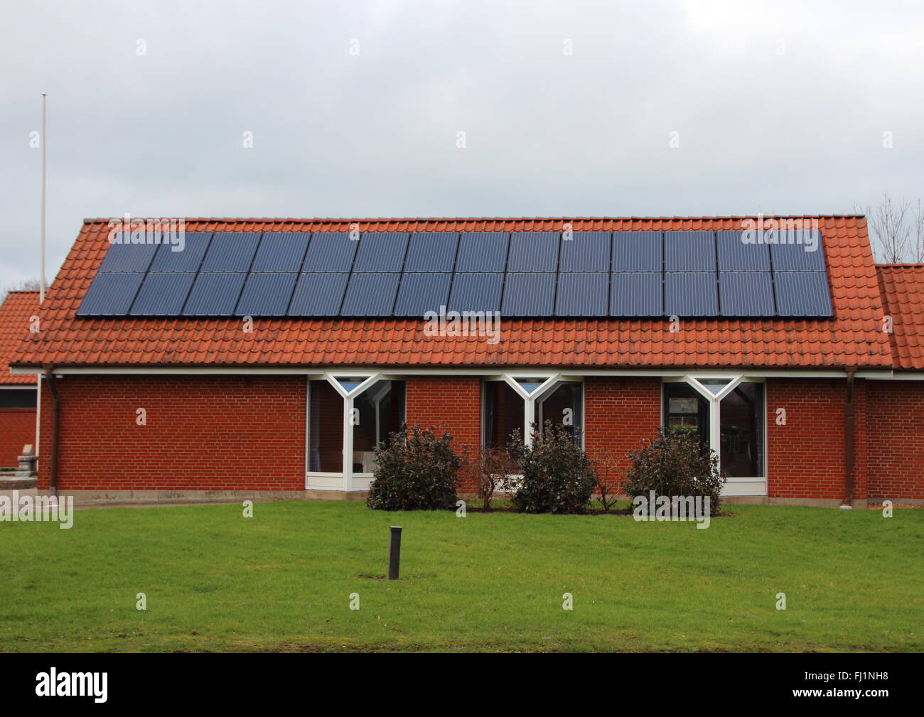 Sonne-Solar-Panel Energiespeicher am Dach des roten Hauses Stockfoto