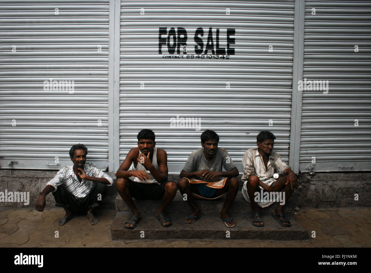 Gruppe indischer Jungs in einer Straße von Mysore sitzen mit "zum Verkauf" schreiben über ihren Köpfen, Indien Stockfoto