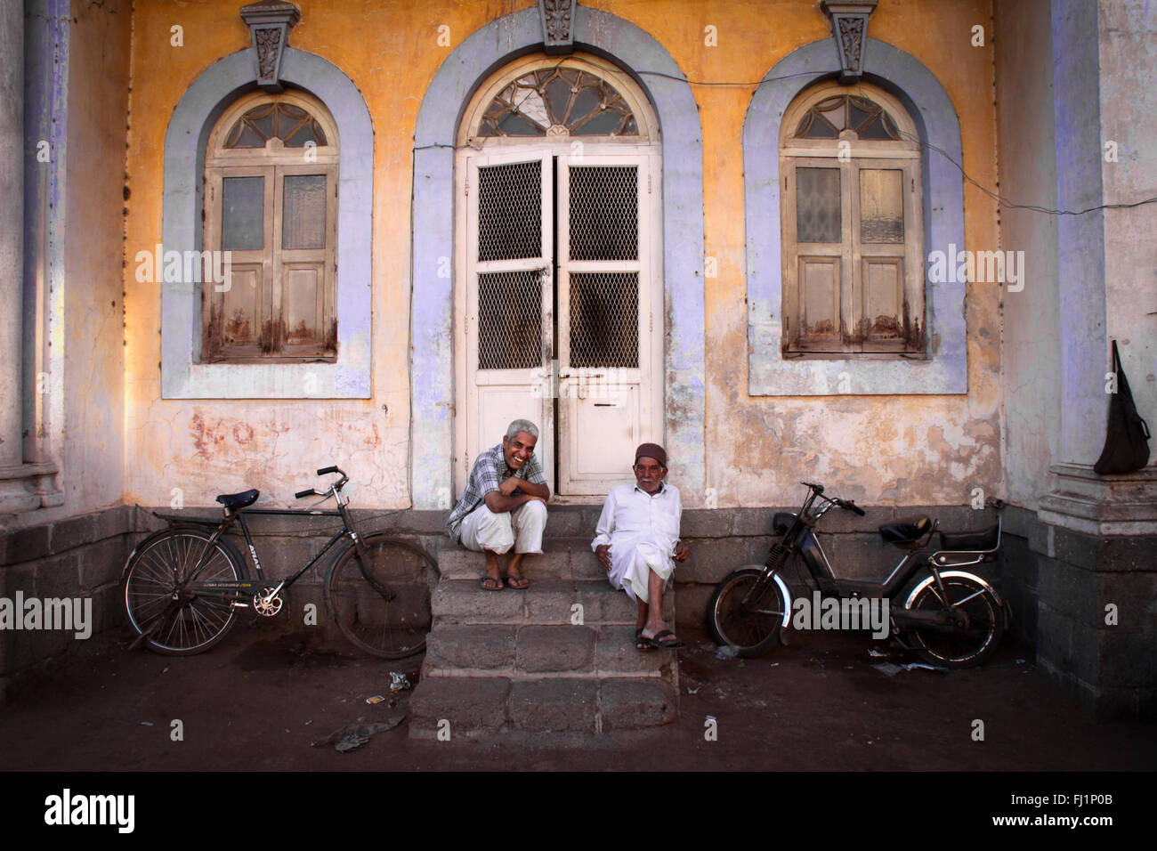 Zwei Männer sitzen am Eingang eines Hauses in Jamnagar, Gujarat, Indien Stockfoto