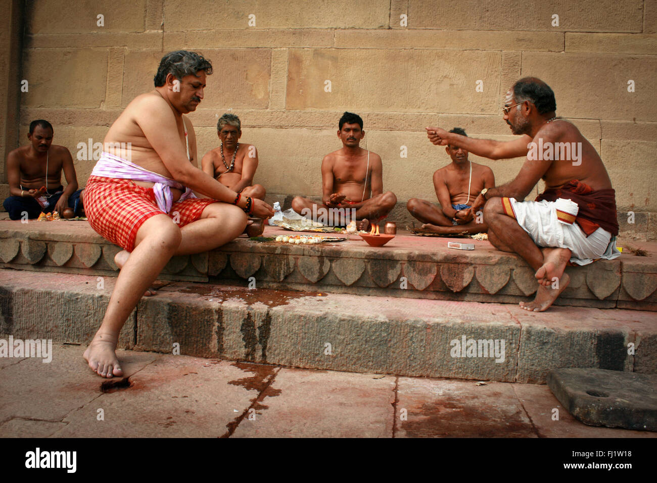 Hinduistische Pilger beten mit Brahman auf einem GHAT von Varanasi, Indien Stockfoto