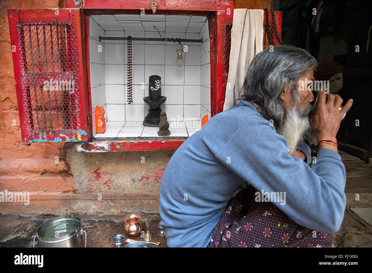 Man Getränke Kaffee in Varanasi, Indien, vor Temple mit Shiva Lingam Stockfoto
