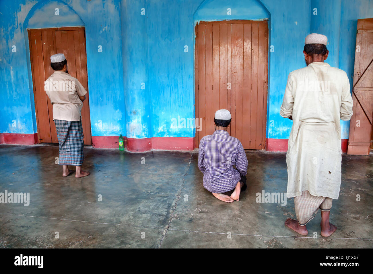 Drei muslimische Männer beten an der Moschee mit blauen Wand in Sreemangal, Bangladesch Stockfoto