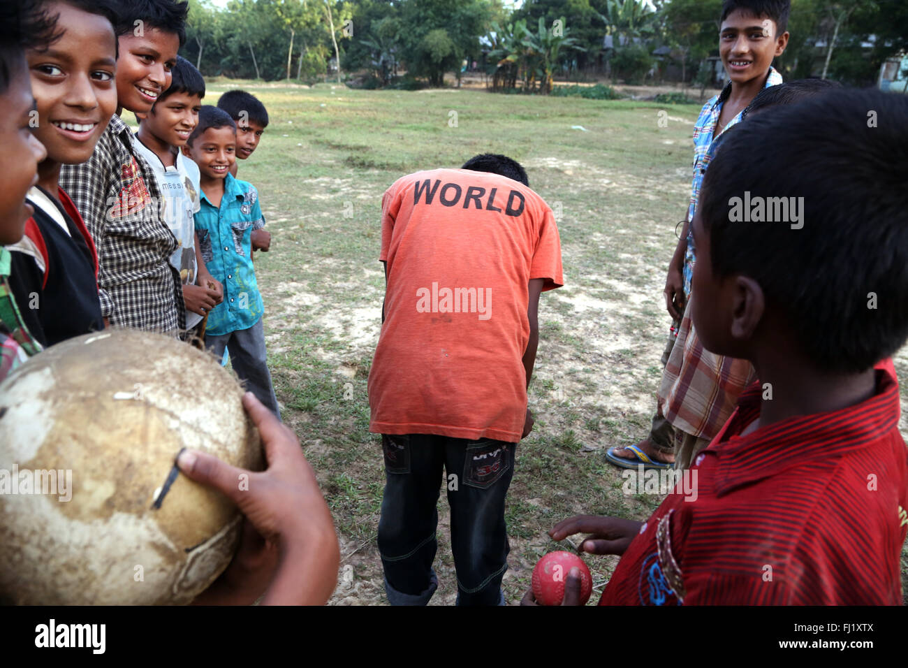 Glücklich lächelnde Kinder spielen Fußball mit 'Welt' t-shirt in Sreemangal, Bangladesch Stockfoto