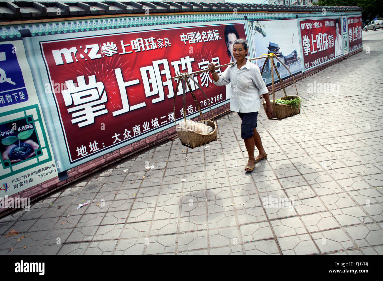 Frau Anbieter zwei Körbe in einer Straße von Jianshui, China Stockfoto