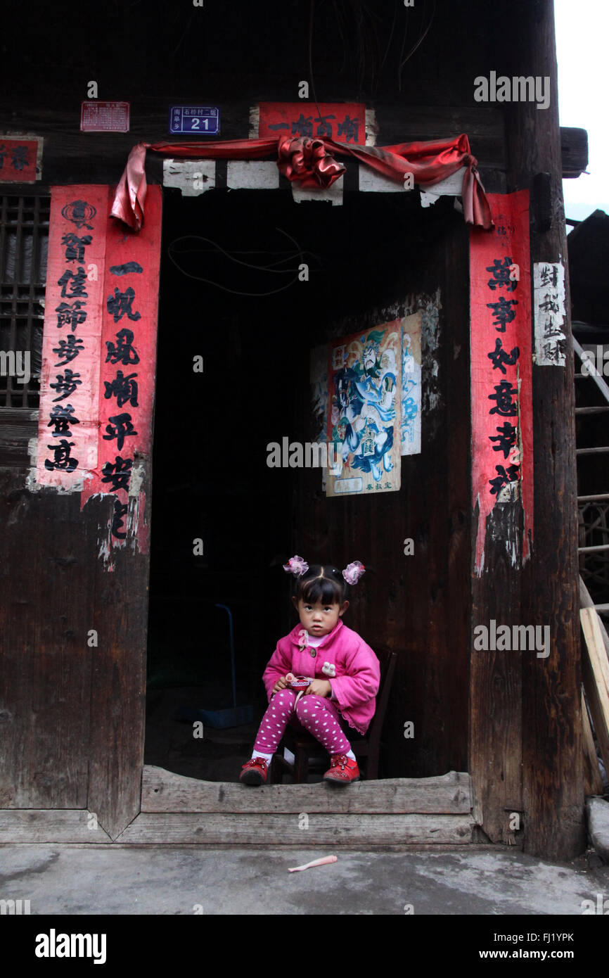 Chinesisches Mädchen am Eingang ihres Hauses im Dorf Shiqiao, Guizhou, China Stockfoto