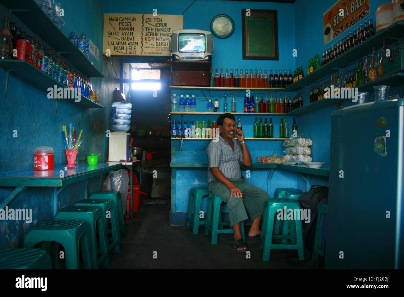 Menschen, die auf dem Handy in kleinen lokalen Restaurant in Denpasar, Bali Stockfoto