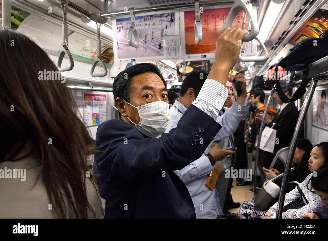 Business Mann mit Mundschutz in den frühen Morgen in der U-Bahn von Tokio, Japan Stockfoto