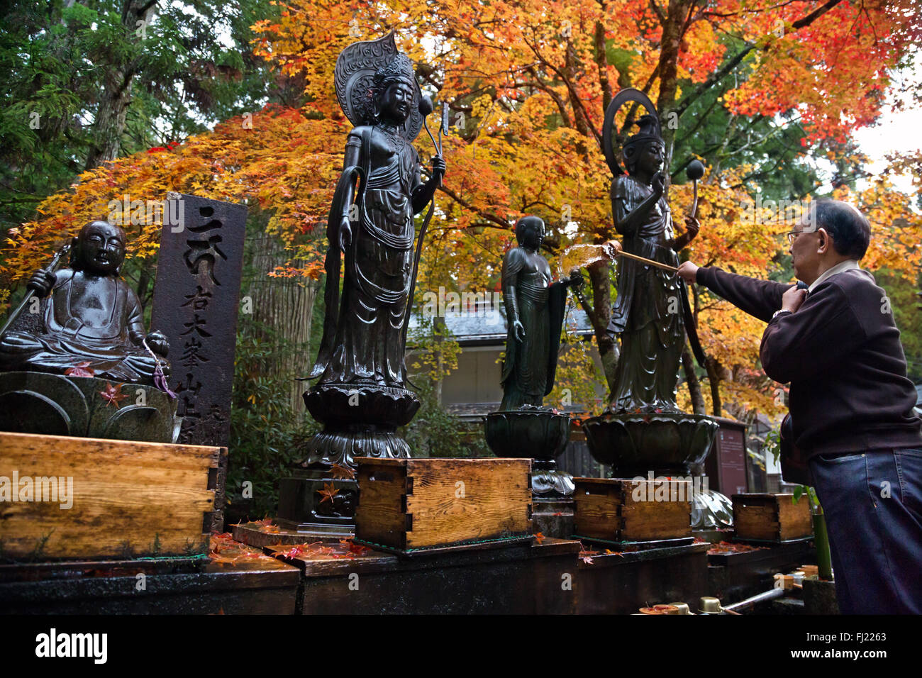 Man gießt Wasser auf buddhistischen Statuen in Okunoin Friedhof, Koyasan Stockfoto