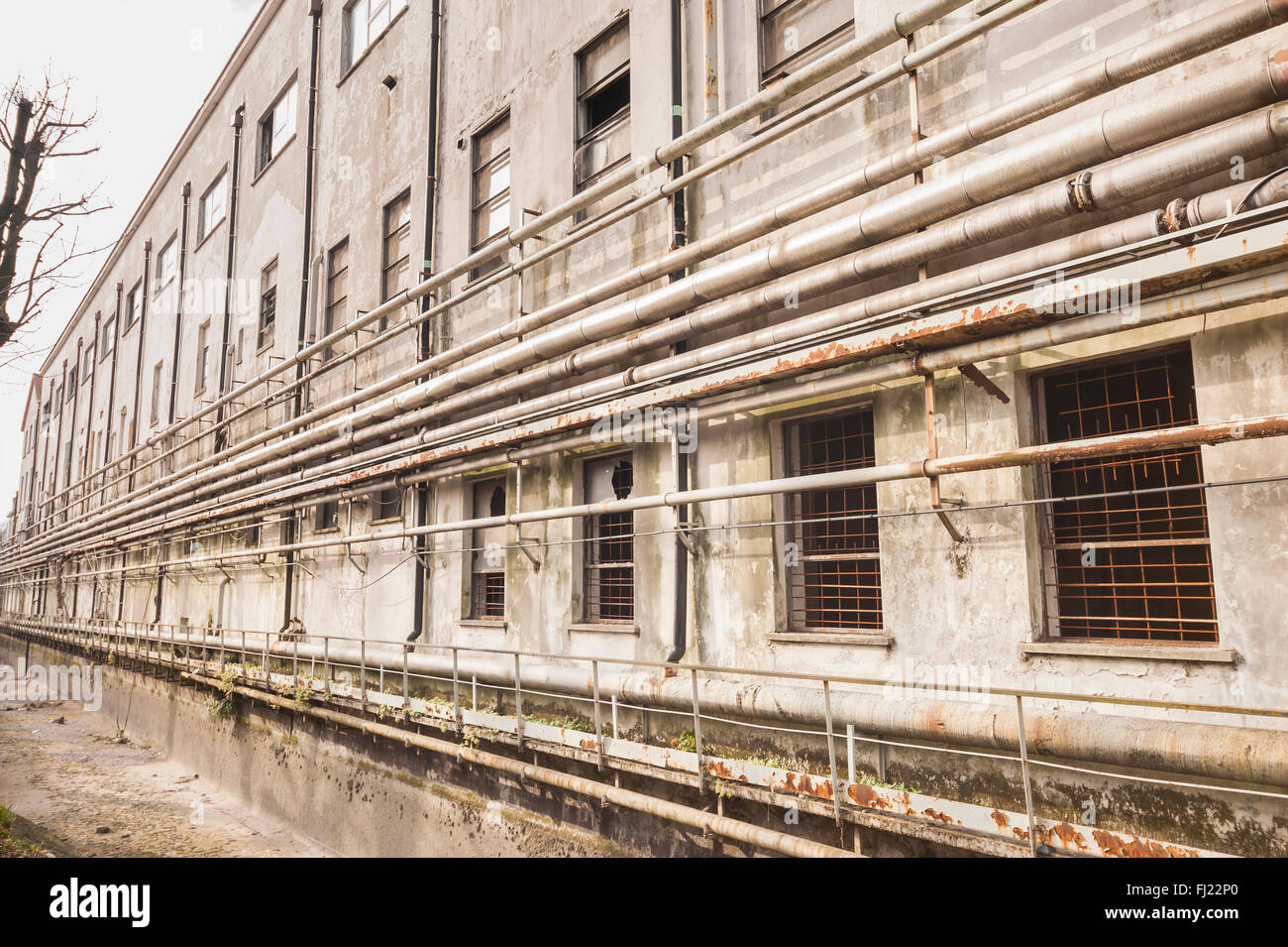Alte Rohre an der Wand außerhalb einer alten verlassenen Fabrik. Stockfoto