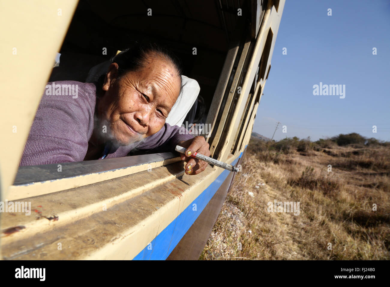 Frau rauchen Cheroot auf einem lokalen Zug, Myanmar Stockfoto