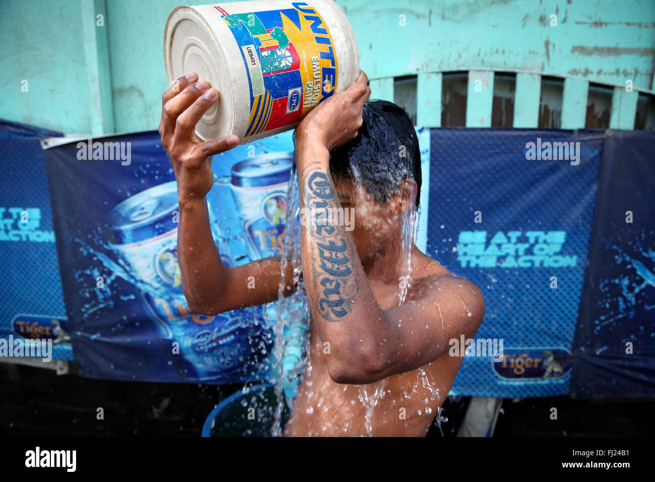 Ein Kerl gießt Wasser auf sich selbst in einer Straße von Rangun, Myanmar Stockfoto