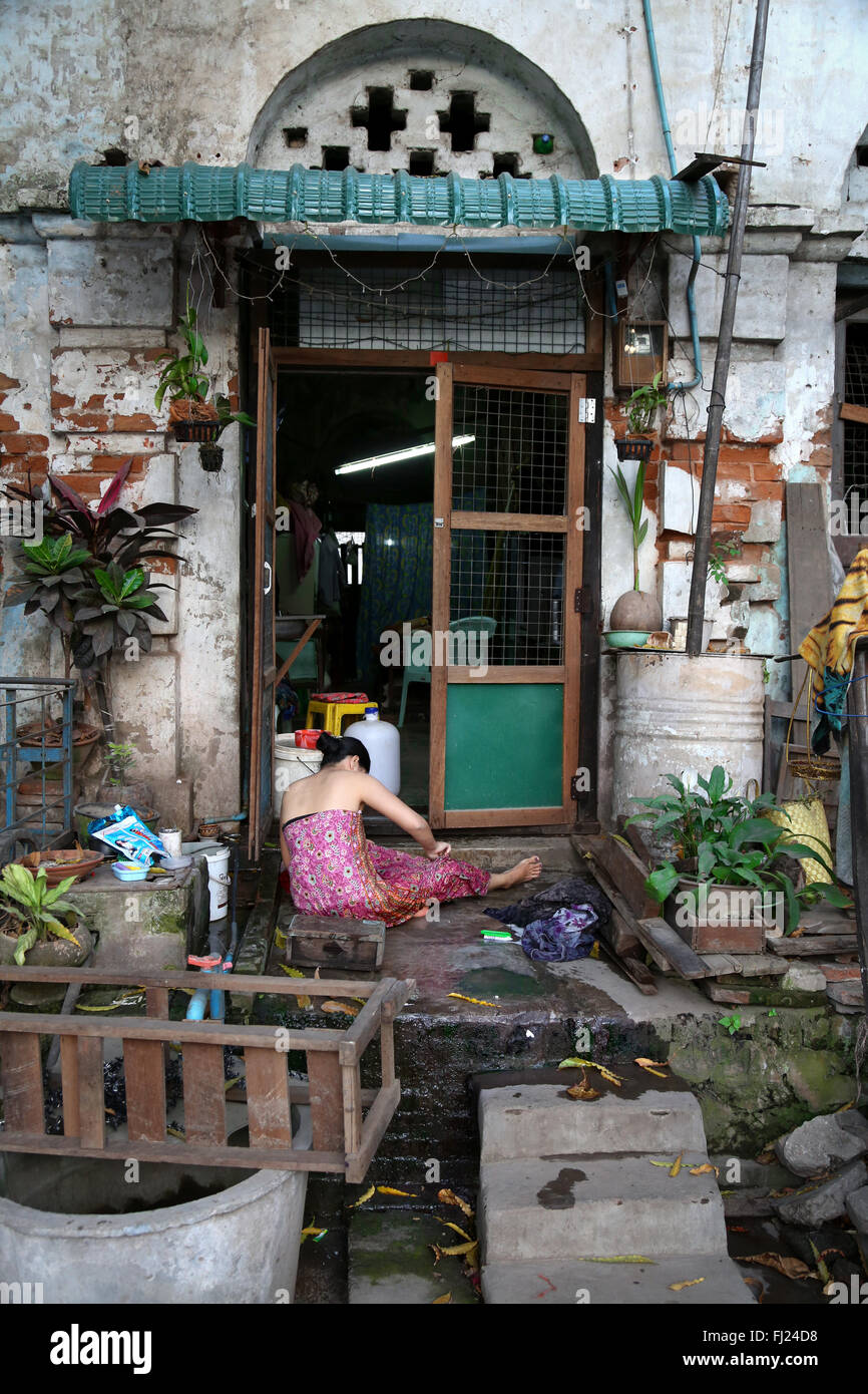 Frau waschen bei Eingang ihres Hauses in Mandalay, Myanmar Stockfoto