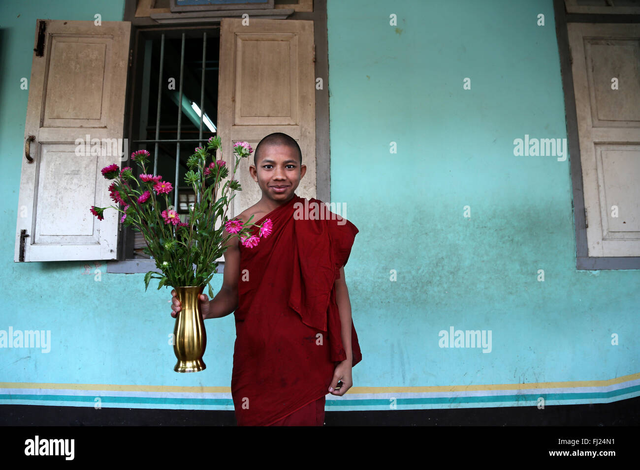 Junger buddhistischer Mönch mit Blumen im Kloster in Amarapura, Myanmar Stockfoto