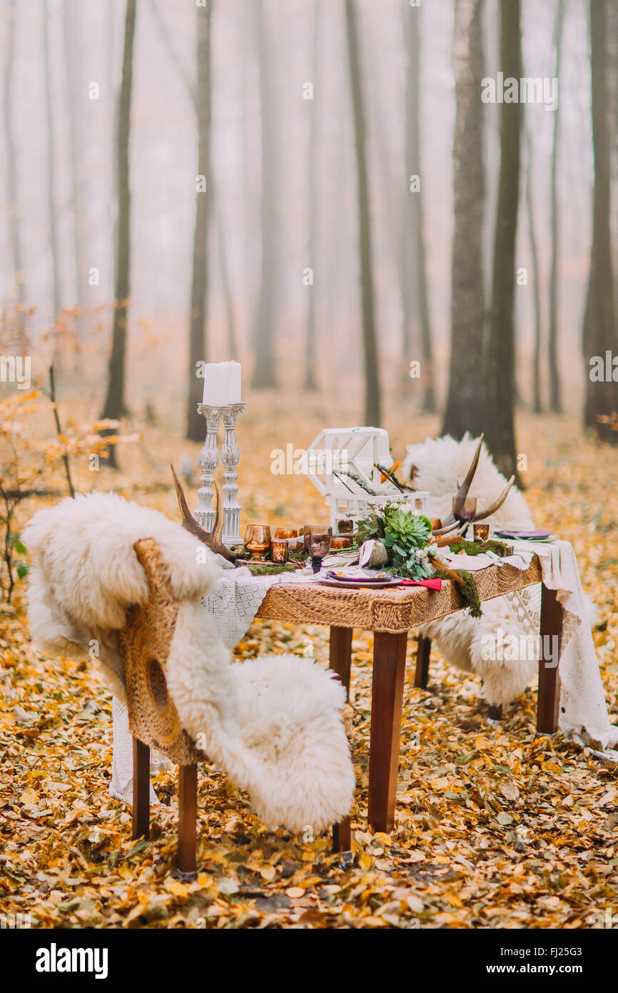 Tabelle im skandinavischen Stil mit Hirsch Hörner und Felle auf Stühlen eingerichtet. Sonnigen Tag auf die herbstlichen Wälder Stockfoto