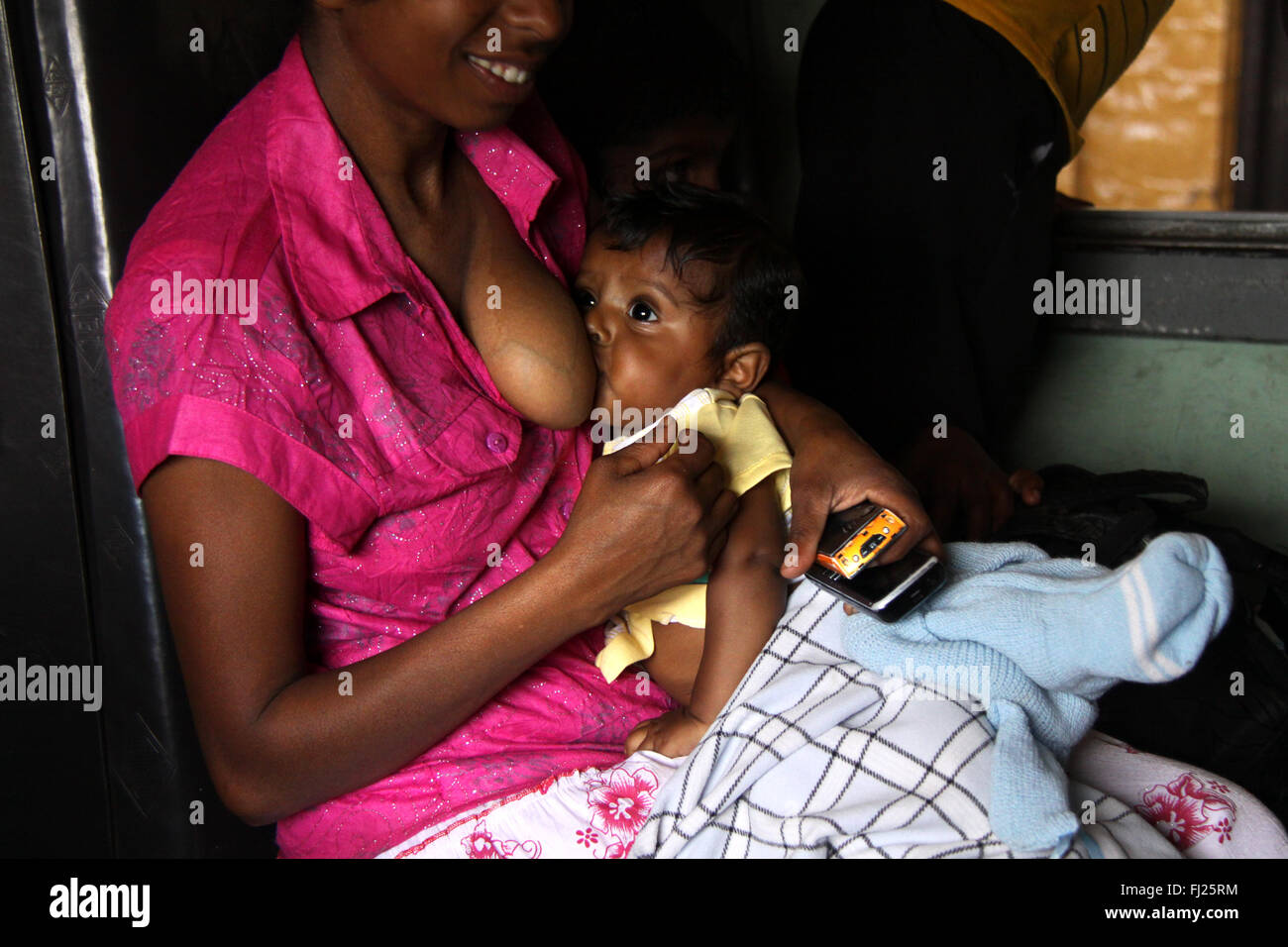 Sri Lankan Frau ihr Baby stillen in Zug Stockfoto