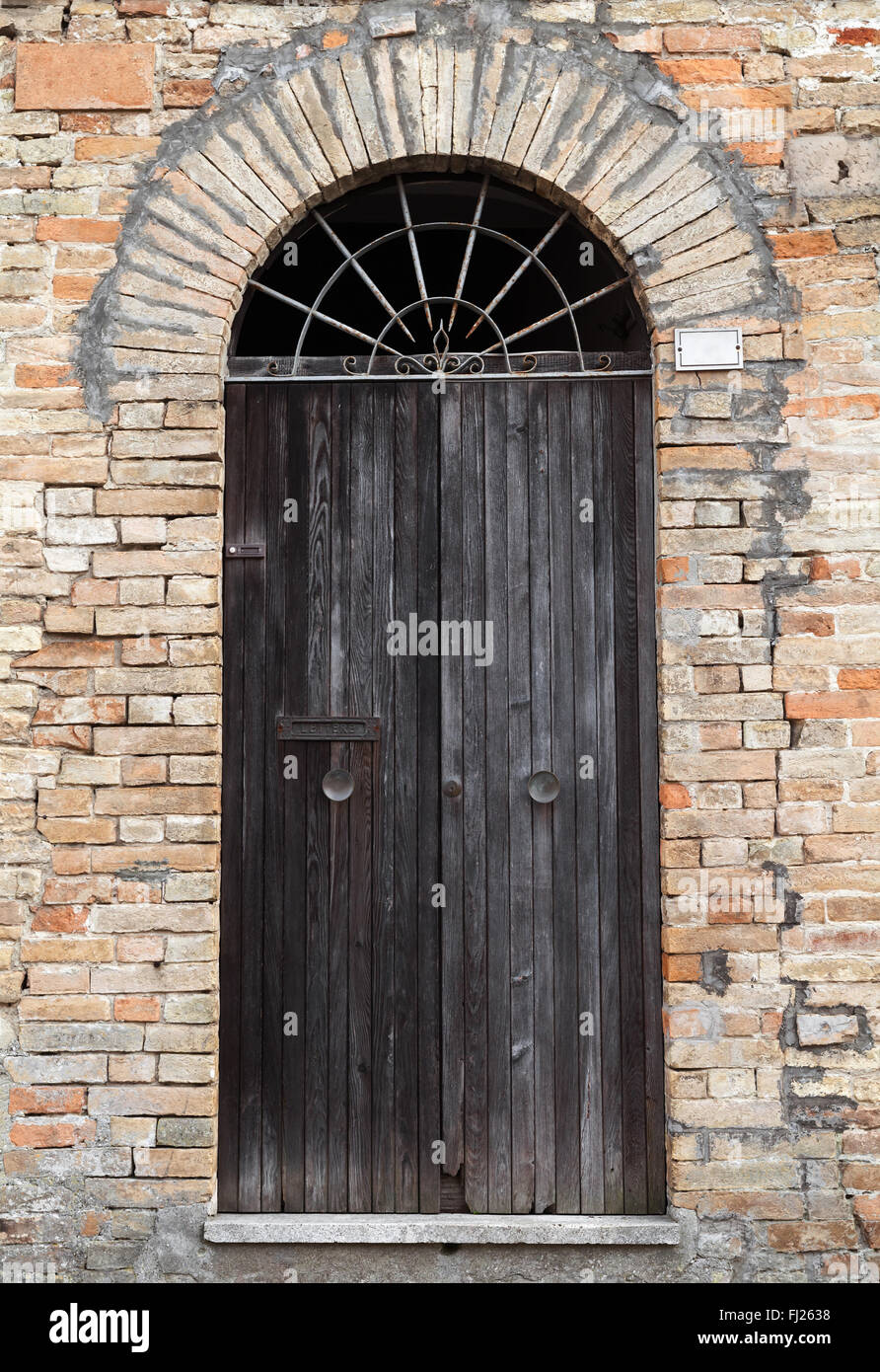 Schwarzen Holztür mit Bogen in alten Steinmauer, Foto Hintergrundtextur Stockfoto