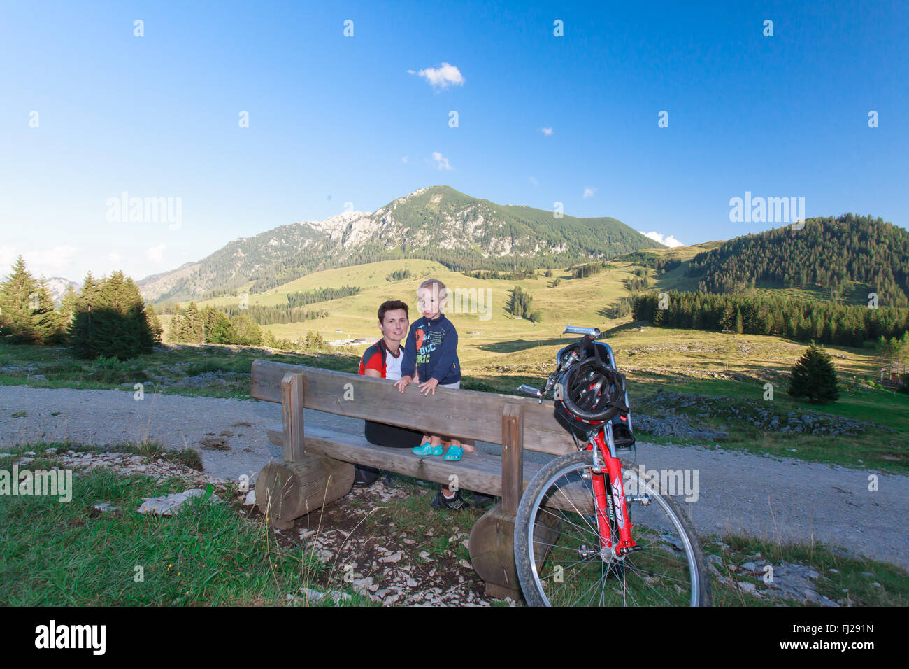 Junge Familie ruht auf der Bank auf einer Radreise. Stockfoto