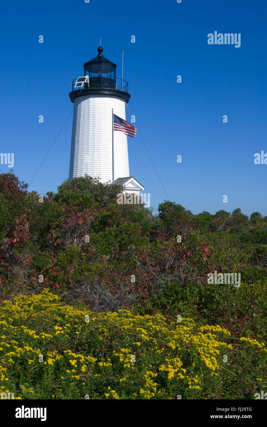 Amerikanische Flagge Wellen vor Cape Pogue Lighthouse Tower an einem sonnigen Tag auf Martha's Vineyard Insel in Massachusetts. Die Insel ist in der Nähe von Cape Cod. Stockfoto