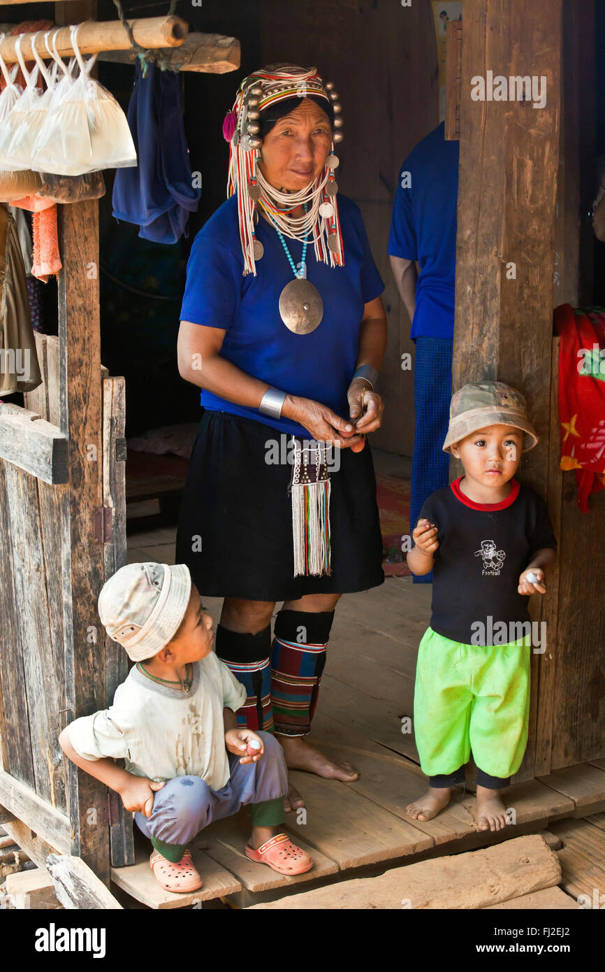 Eine AKHA Großmutter trägt ihre Stämme aufwändigen Kopfschmuck aus Perlen, Silber Münzen und hand ragte Baumwolle während eine Baby-/Kinderbetreuung Stockfoto