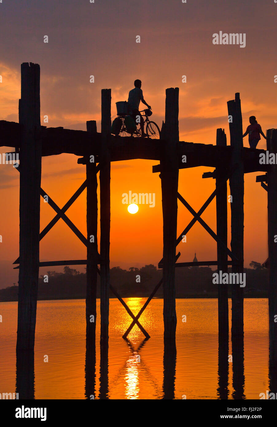 Die BURMESISCHEN Verwendung das Teakholz Brücke U KLANGKUNST um zu pendeln über den Taungthaman-See bei Sonnenaufgang - AMARAPURA, MYANMAR Stockfoto