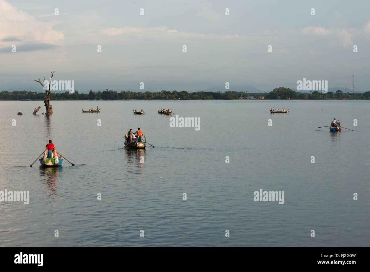 AMARAPURA, Myanmar – die U Bein Bridge erstreckt sich über den Taungthaman Lake bei Mandalay. Die 1,2 Kilometer lange Teakholzkonstruktion, die vermutlich die älteste und längste Teakholzbrücke der Welt ist, ist vom Himmel her umrahmt. Einheimische Fußgänger und Mönche überqueren die Brücke, während Touristen die berühmte Szene beobachten, die besonders bei Sonnenuntergang beliebt ist. Stockfoto