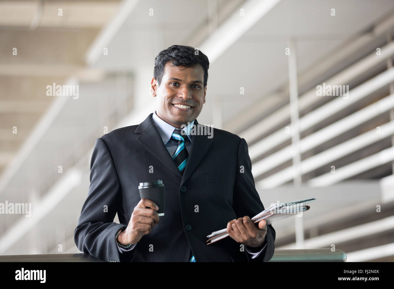 Porträt von ein indischer Geschäftsmann vor modernen Bürogebäude. Asiatische Geschäftsmann lächelnd & in die Kamera schaut. Stockfoto