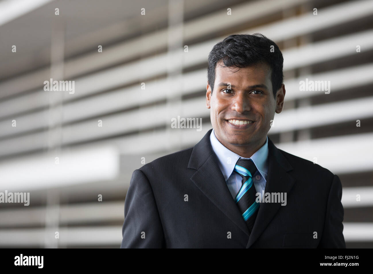 Porträt von ein indischer Geschäftsmann vor modernen Bürogebäude. Asiatische Geschäftsmann lächelnd & in die Kamera schaut. Stockfoto