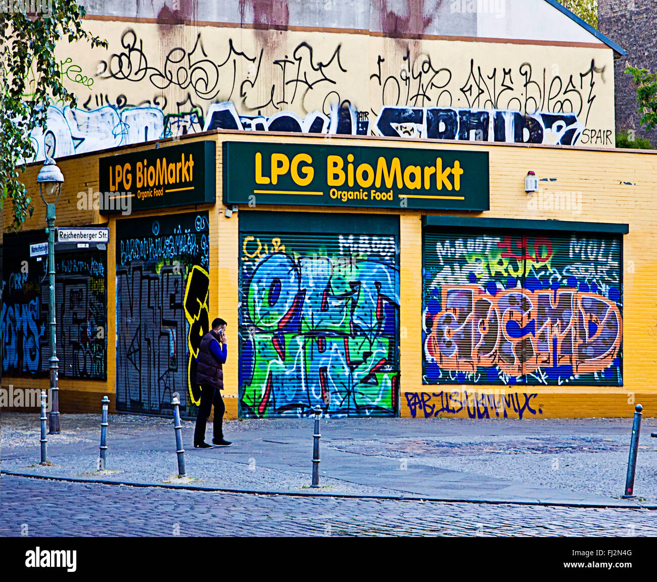 Berlin, Mann mit Handy in der Nähe von Rollos Store gehen und Gebäude mit Straßenkunst graffiti Stockfoto