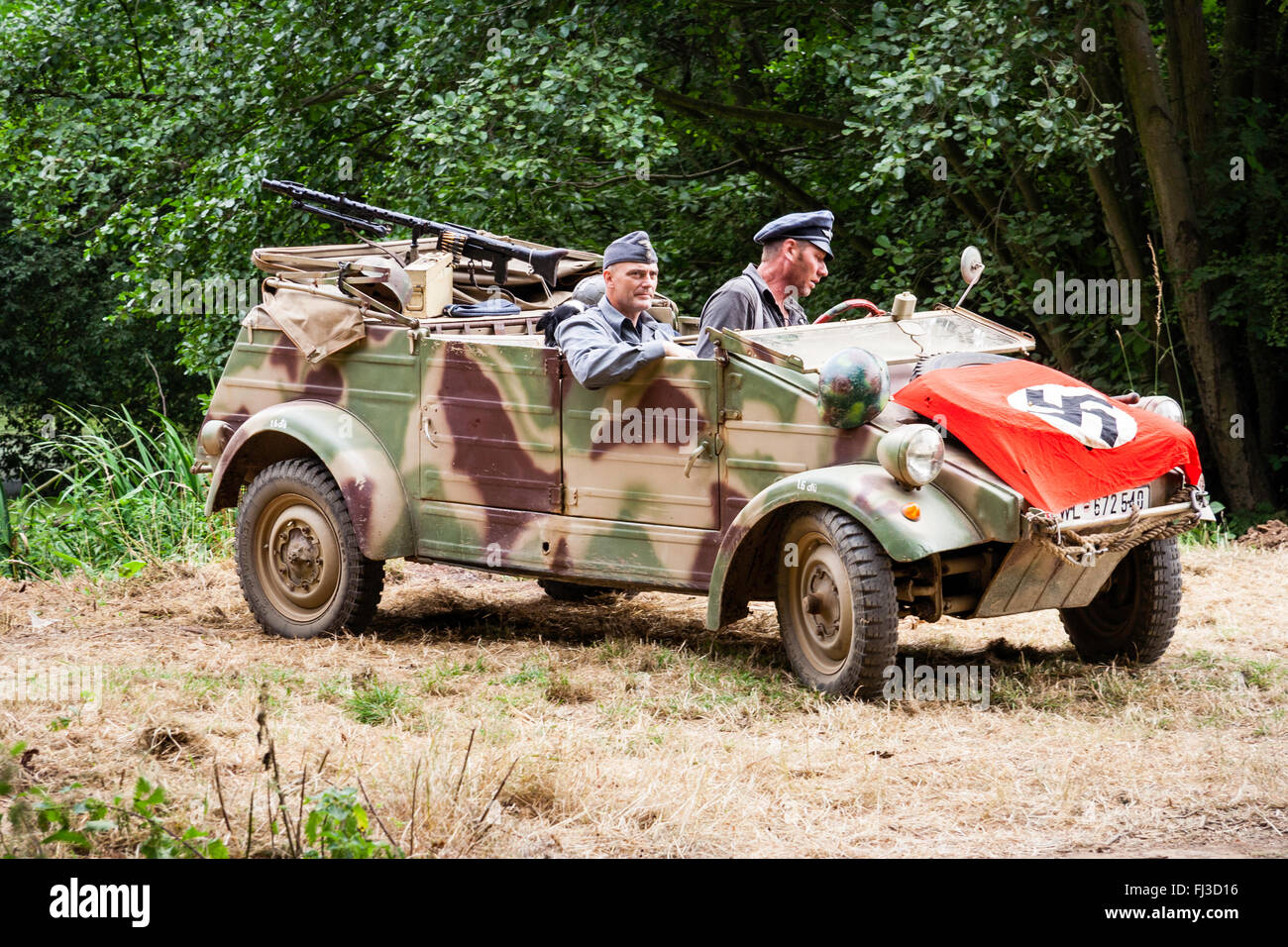 Krieg und Frieden zeigen, England. Zweiten Weltkrieg Re-enactment. Deutsche getarnt Kubel Auto mit zwei Offiziere und Nazi Flag über Motorhaube drapped, Haube. Stockfoto