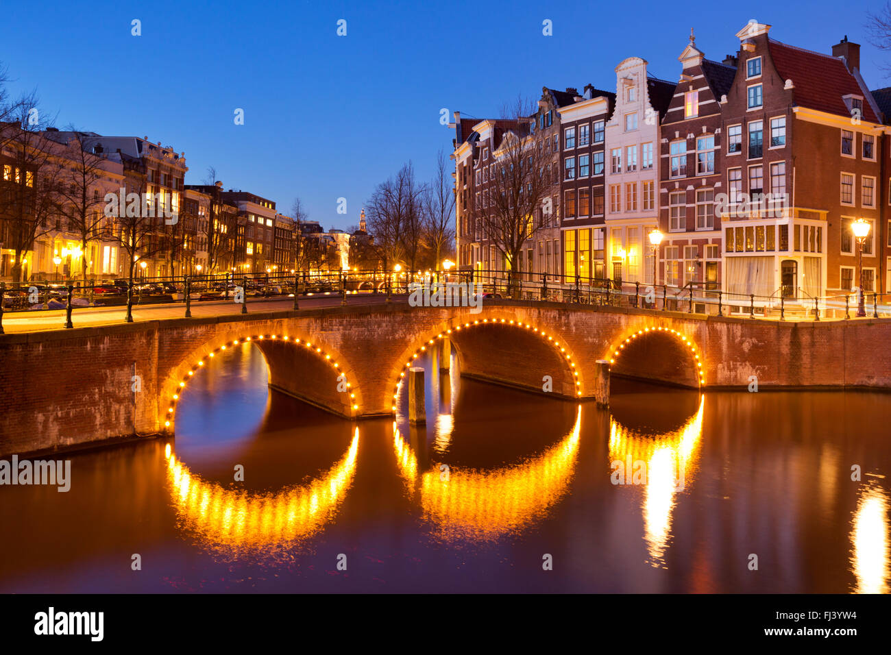 Eine Brücke über einen Kanal in der Stadt Amsterdam, die Niederlande in der Nacht. Stockfoto