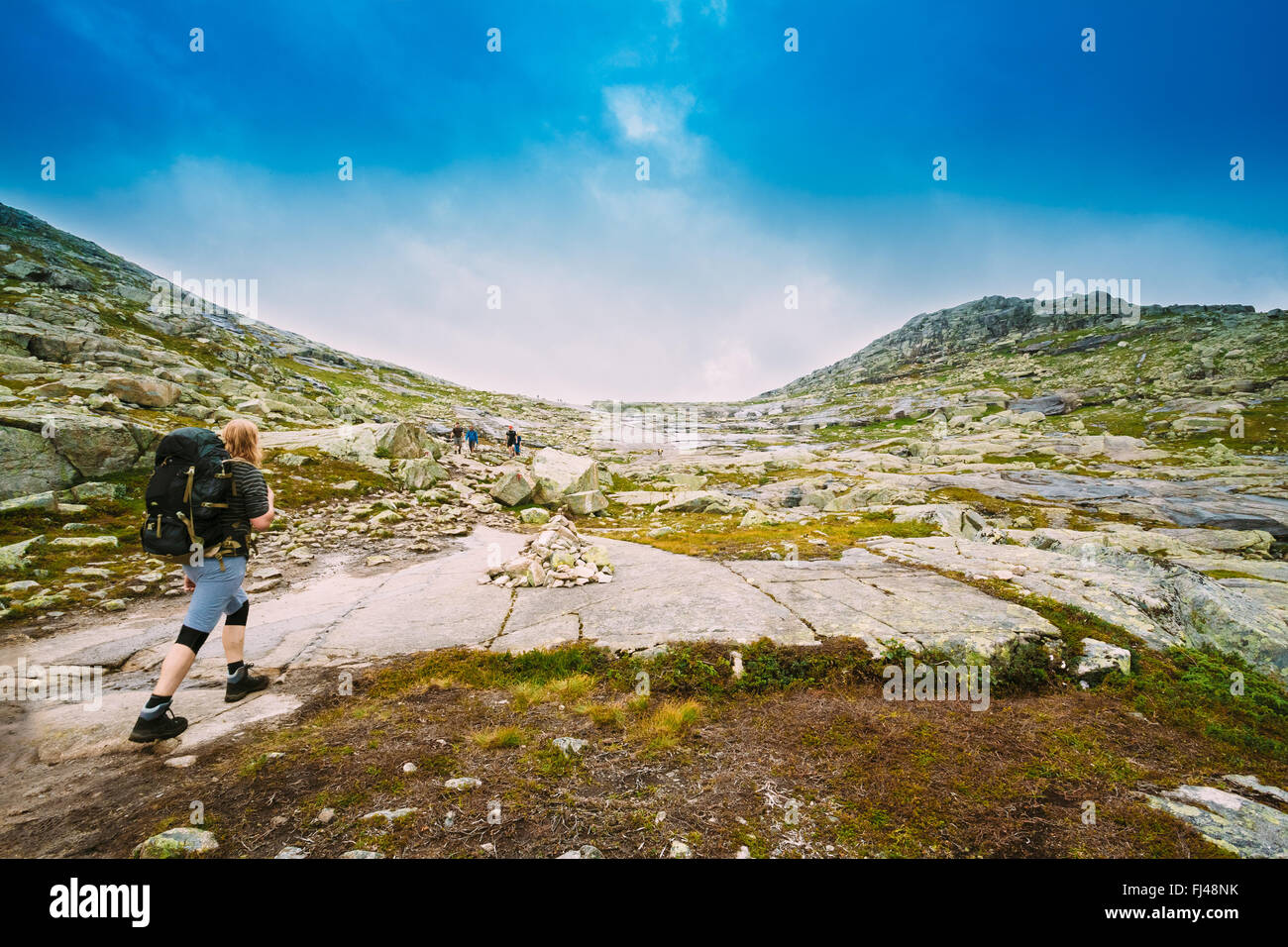 Junger Mann geht auf einem Berg Wanderweg in den Bergen von Norwegen. Pfad zu den natürlichen Sehenswürdigkeiten der Trolltunga - Trolle Tonne Stockfoto