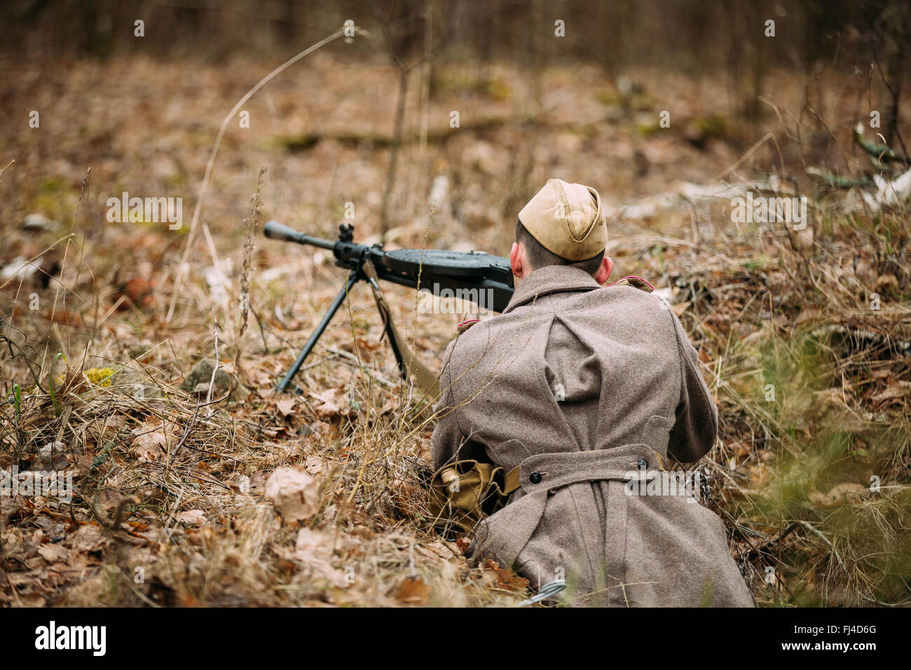 Nicht identifizierte Re-Enactor gekleidet als Zweiter Weltkrieg sowjetische russischer Soldat mit Maschinengewehr im Waldboden versteckt. Stockfoto