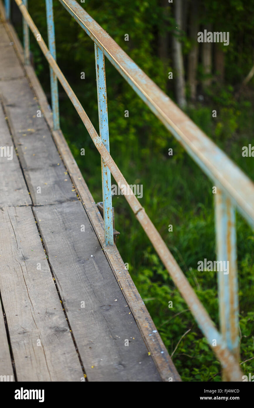 alte Brücke aus Holzbrettern mit rostigen Geländer Stockfoto