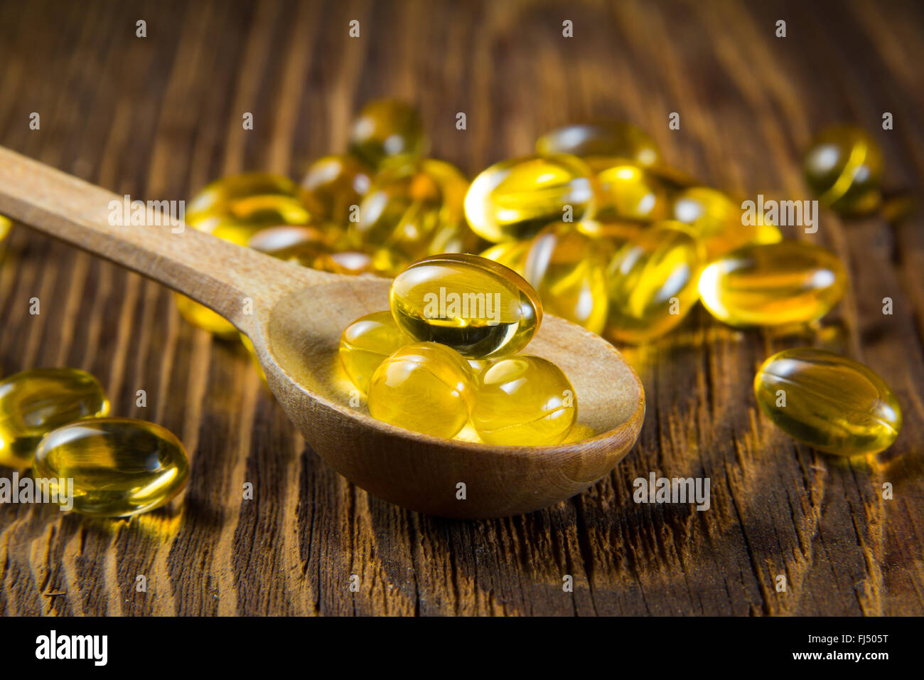Lebertran, Omega 3, Vitamin D Kapseln auf Holzlöffel Stockfoto