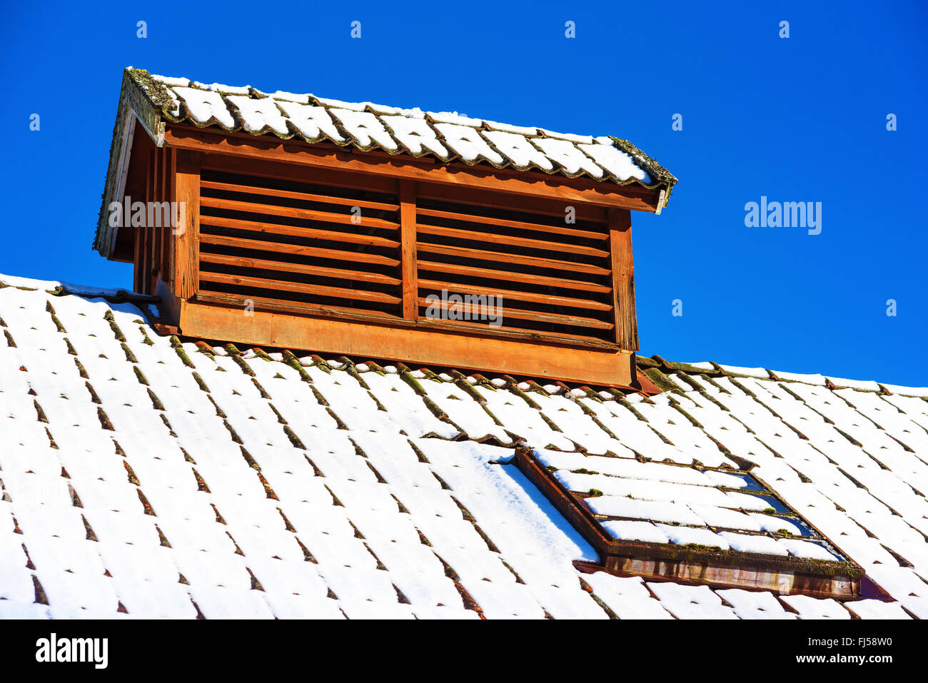 Eine Air Vent Abdeckung auf dem Dach gebaut, um ein kleines Haus aussehen. Blauen Himmel im Hintergrund. Schnee am Dach. Stockfoto