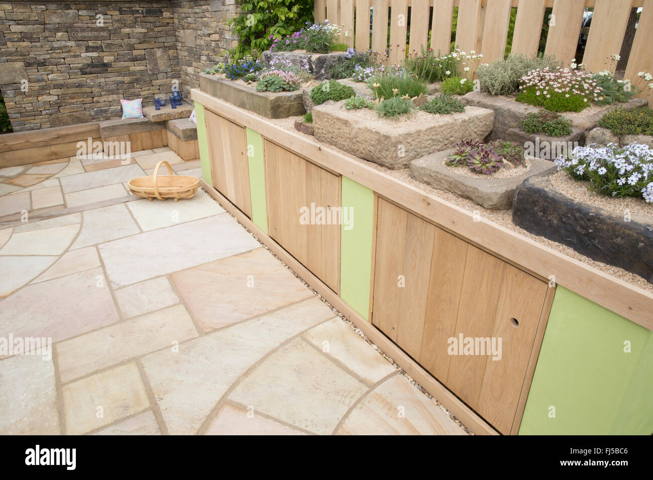 Kleiner städtischer Garten Steinplatten Terrasse Aufbewahrungsschränke eine Ausstellung von alpinen Pflanzen in Steintrog Container Container - Sitzbereich Steinbank UK Stockfoto