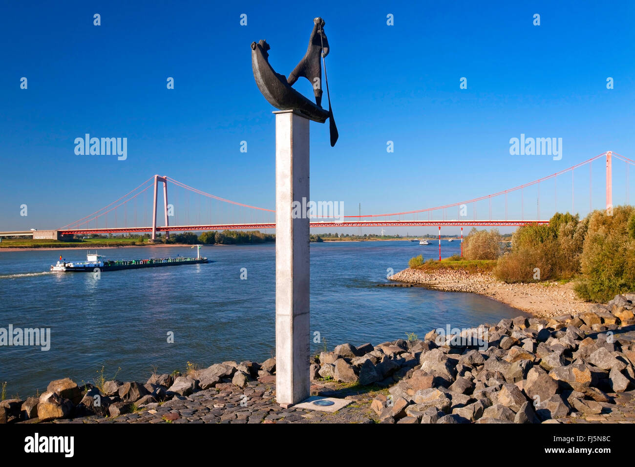 Skulptur Fährmann mit Cargo Schiff und Brücke über den Rhein, Deutschland, Nordrhein-Westfalen, Niederrhein, Emmerich Stockfoto