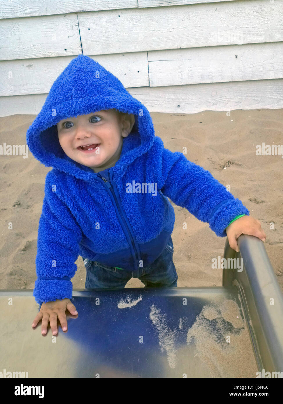glückliche kleine Junge stehend auf einer Folie Stockfoto