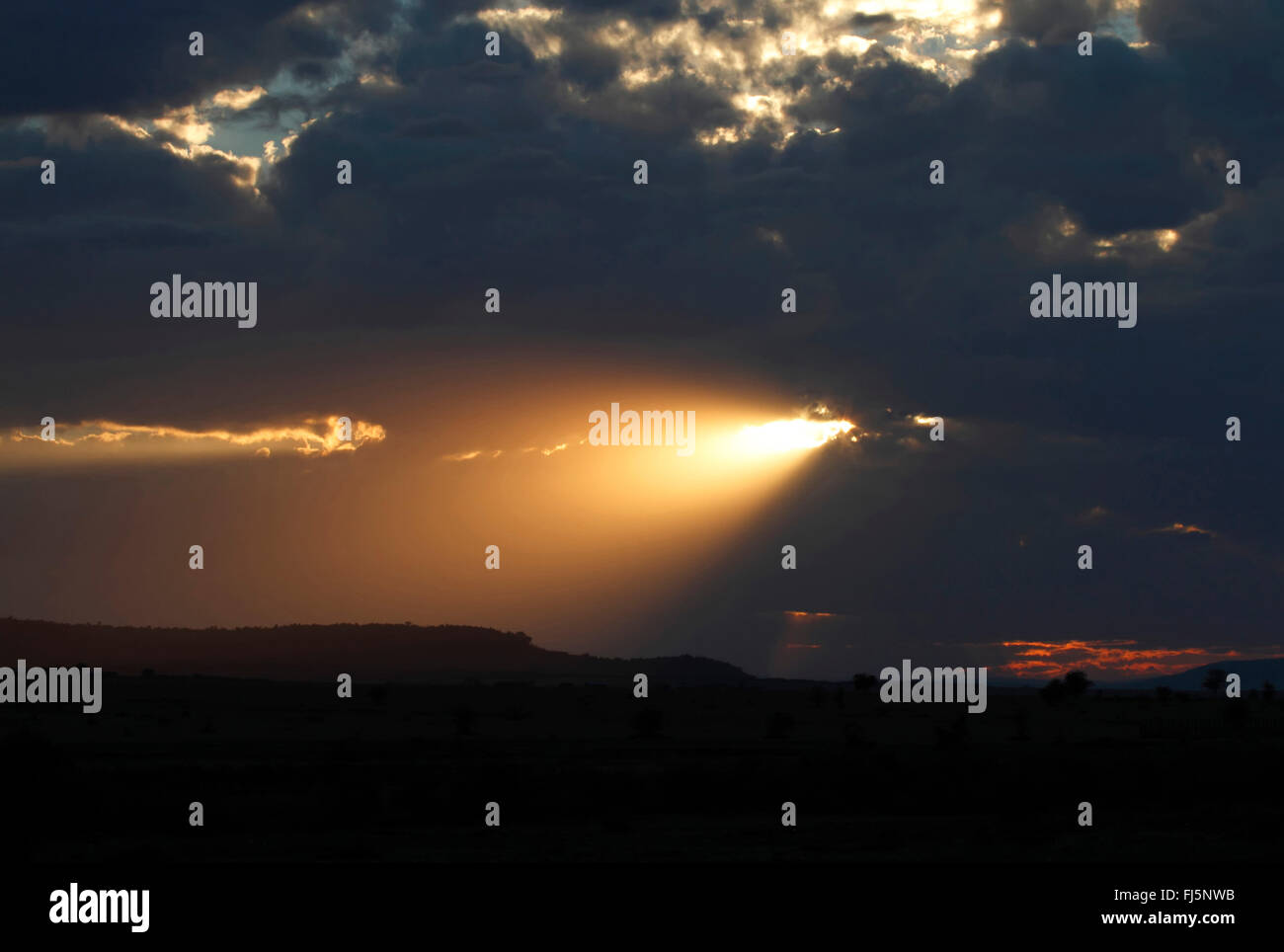 Einstellung der Sonne durch die Wolken, Kenia, Masai Mara Nationalpark Stockfoto